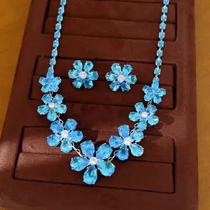 Close-up of elegant blue zircon flower necklace and earrings set on velvet tray