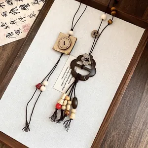Collier artisanal de style ethnique vintage avec pendentif bouton fleur en bois et glands.