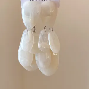 Détail de boucles d'oreilles élégantes en résine crème avec texture marbrée et glands