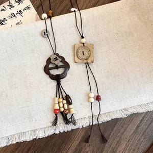 Colliers ethniques avec pendentifs fleurs et boutons présentés sur un tissu en lin