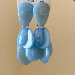 Vue détaillée des boucles d'oreilles pendantes en résine bleue, style vacances.