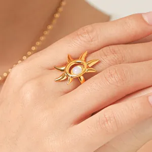 Dettagliato primo piano di un anello a sole in acciaio dorato con pietra opale bianca al dito