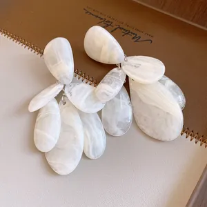 Détail macro de boucles d'oreilles en résine goutte d'eau blanche avec texture marbrée