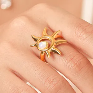 Dettaglio macro di un anello aperto dorato a forma di sole con pietra iridescente.