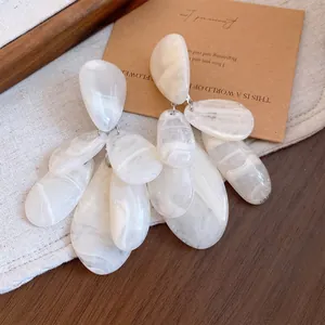 Vue détaillée des boucles d'oreilles en résine blanche à motif de goutte d'eau