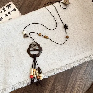 Close-up of a vintage folk-style wooden flower pendant necklace on linen cloth