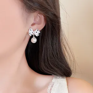 Detailed close-up showing polka dot bowknot earrings with white pearl drop on a model