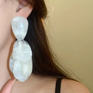 Gros plan détaillé de boucles d'oreilles en résine française avec texture de marbre