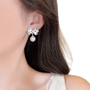 Sweet white polka dot bowknot earrings with elegant pearl drop shown on model ear