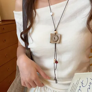 Close-up of a retro button pendant long necklace styled on a white off-shoulder top