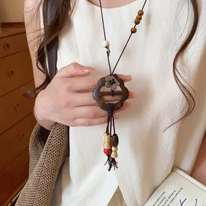 Close-up of a vintage ethnic style flower button wooden pendant necklace on a female model