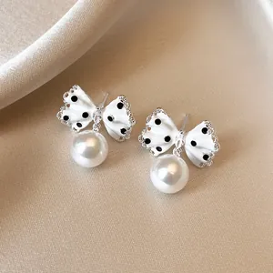 Detail view of white polka dot butterfly bow earrings with pearl pendant