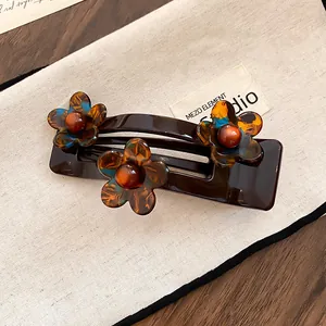 Gros plan d'une pince à cheveux fleur en acrylique marron avec une texture ambrée.