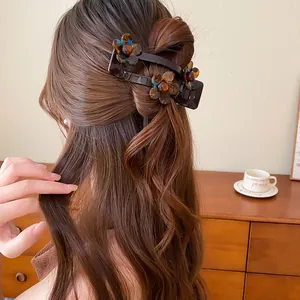 Vue détaillée d'une pince à cheveux fleur en acrylique marron dans une demi-queue