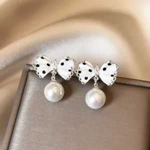 Detailed view of white polka dot bowknot earrings with lustrous pearl pendants.