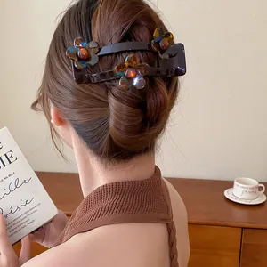 Vue détaillée d'une pince à cheveux à fleurs en acrylique marron dans une coiffure