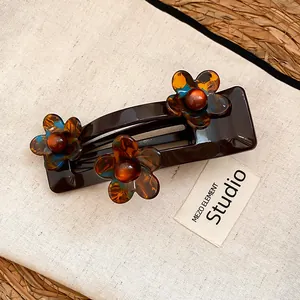 Vue détaillée d'une pince à cheveux chocolat avec trois fleurs en acrylique écaille