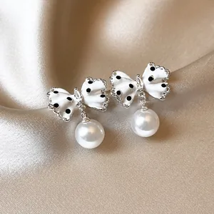 Detailed macro view of polka dot bow earrings with elegant white pearl drop pendants