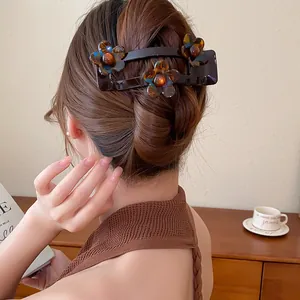 Vue détaillée d'une pince à cheveux fleur en acrylique marron chocolat dans un chignon
