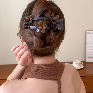 Détail d'une élégante pince à cheveux à fleurs en acrylique marron chocolat sur un chignon