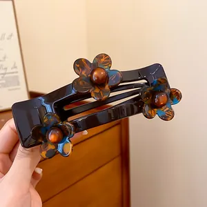 Gros plan sur une pince à cheveux élégante en acrylique marron avec fleurs en écaille