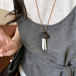 Detailansicht einer minimalistischen Lederhalskette mit weißem Perlenquasten-Anhänger am Model
