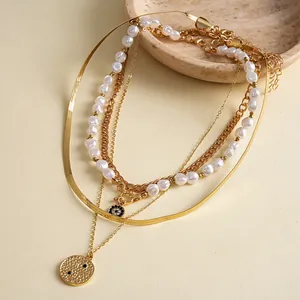 Detailed view of 4-piece layered gold chain necklace set with baroque pearls and disc charms