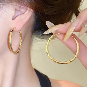 Gros plan sur ces boucles d'oreilles créoles dorées avec texture plissée chic
