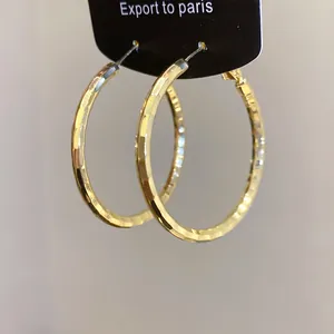 Gros plan détaillé de boucles d'oreilles créoles dorées avec une texture martelée chic.