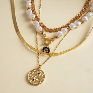 Close-up of 4-piece multilayer gold necklace with elegant pearls and engraved pendants