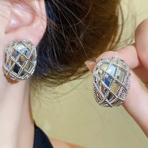 Primo piano di eleganti orecchini a lobo ovali in maglia d'argento con trama finemente lavorata