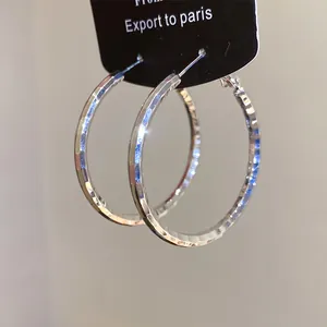 Gros plan sur des boucles d'oreilles créoles argentées à texture martelée