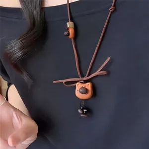Primer plano de un collar con colgante de oso de madera vintage con un cordón marrón.