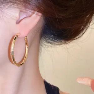 Gros plan de boucles d'oreilles créoles dorées martelées avec surface texturée et aiguilles