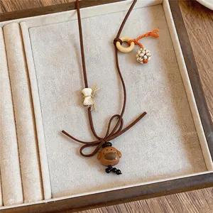 Primer plano de un collar vintage con colgante de oso de madera en cordón marrón