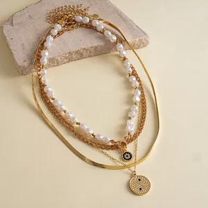 Set of 4 layered gold-tone necklaces with baroque pearls and round textured pendants.