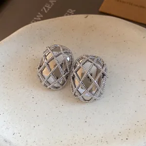 Dettaglio orecchini a lobo ovali argento con design a maglia intrecciata chic.