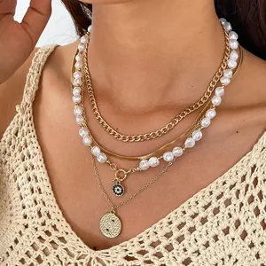 Detailed view of a four-piece layered necklace set with gold chains and faux pearls