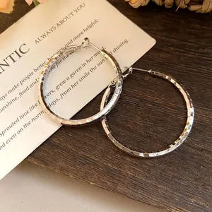 Gros plan sur des boucles d'oreilles créoles argentées avec un fini martelé unique