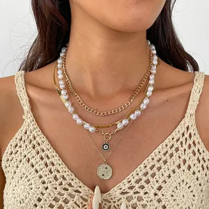 Close-up detail of layered gold chain and white pearl necklace set with round pendants