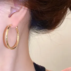 Gros plan détaillé de boucles d'oreilles créoles dorées à surface facettée et design élégant