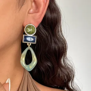 Primo piano di orecchini vintage in acrilico geometrico con resina marmorizzata blu e verde