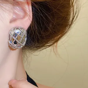 Primo piano di orecchini a perno ovali in argento a griglia indossati da una modella