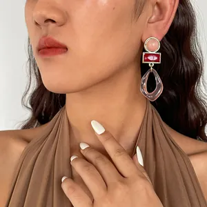 Primo piano di orecchini pendenti geometrici vintage in acrilico rosa e rossi su modella