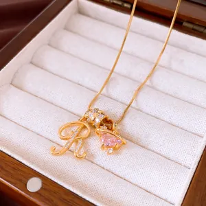 Detail van 18k vergulde ketting met zirkonia letter R en roze kristallen hangers