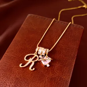 Detail van de 18k vergulde ketting met glanzende zirkonia hart en letter R hangers