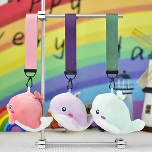 Detail of three cute colorful plush whale keychains hanging from a silver metal stand