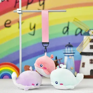 Close-up of adorable whale plush keychains in pink, purple, and blue hanging from a display stand