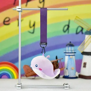 Adorable purple plush whale keychain hanging on a display stand with beach props.