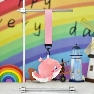 Detail view of a cute pink whale plush keychain hanging from a fabric strap for bags